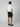 A man faces away from the camera wearing a white short-sleeve polo, PROJEK RAW MENS CHINO SIGNATURE SHORT 8 in dark navy, and brown loafers against a plain light gray background.