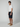 A young man stands in a studio wearing PROJEK RAW MENS DRAWSTRING CHINO SHORT, a white t-shirt, and tan sneakers, looking at the camera with a neutral expression against a plain light background.