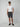 A man in sunglasses, a plain white tee, PROJEK RAW MENS DRAWSTRING CHINO SHORT in dark gray, and black slip-on shoes stands against a light background with one hand in his pocket.