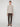A person faces forward against a white background, wearing a light beige sweater, PROJEK RAW MENS 5-POCKET SOLID BUNGEE PANT in dark brown, and matching brown shoes.