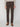 A person is shown from shoulders to feet wearing PROJEK RAW MENS 5-POCKET SOLID BUNGEE PANT in dark brown, paired with a light beige sweater and brown loafers, standing against a plain white background.