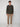 A young man stands against a light gray background, wearing a dark long-sleeve henley shirt, PROJEK RAW MENS 5-POCKET SOLID BUNGEE CHINO PANT, and white sneakers. He faces forward with a neutral expression and relaxed posture.