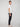 A man in profile stands against a plain light background, wearing a white tee, PROJEK RAW MENS 5-POCKET SOLID BUNGEE CHINO PANT, and white sneakers. He looks ahead neutrally with arms relaxed at his sides.