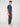A young man with short curly brown hair wears a navy short-sleeve shirt, PROJEK RAW MENS SOLID BUNGEE FASHION CHINO PANT in a tailored fit, and white sneakers, standing sideways and looking at the camera against a white background.