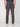 A man stands facing away, wearing PROJEK RAW MENS SOLID BUNGEE FASHION CHINO PANT in dark gray with white sneakers, his arms relaxed at his sides against a plain white background.