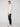 A person stands in profile against a plain background, wearing a white textured zip-neck sweater, PROJEK RAW MENS SOLID BUNGEE JOGGER pants with an elasticized waistband, and white sneakers with brown soles.