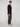 A young man stands sideways, facing the camera in a long-sleeve black shirt and PROJEK RAW MENS SOLID BUNGEE JOGGER pants with an elastic waist and modern fit, paired with white chunky-soled sneakers against a light gray background.