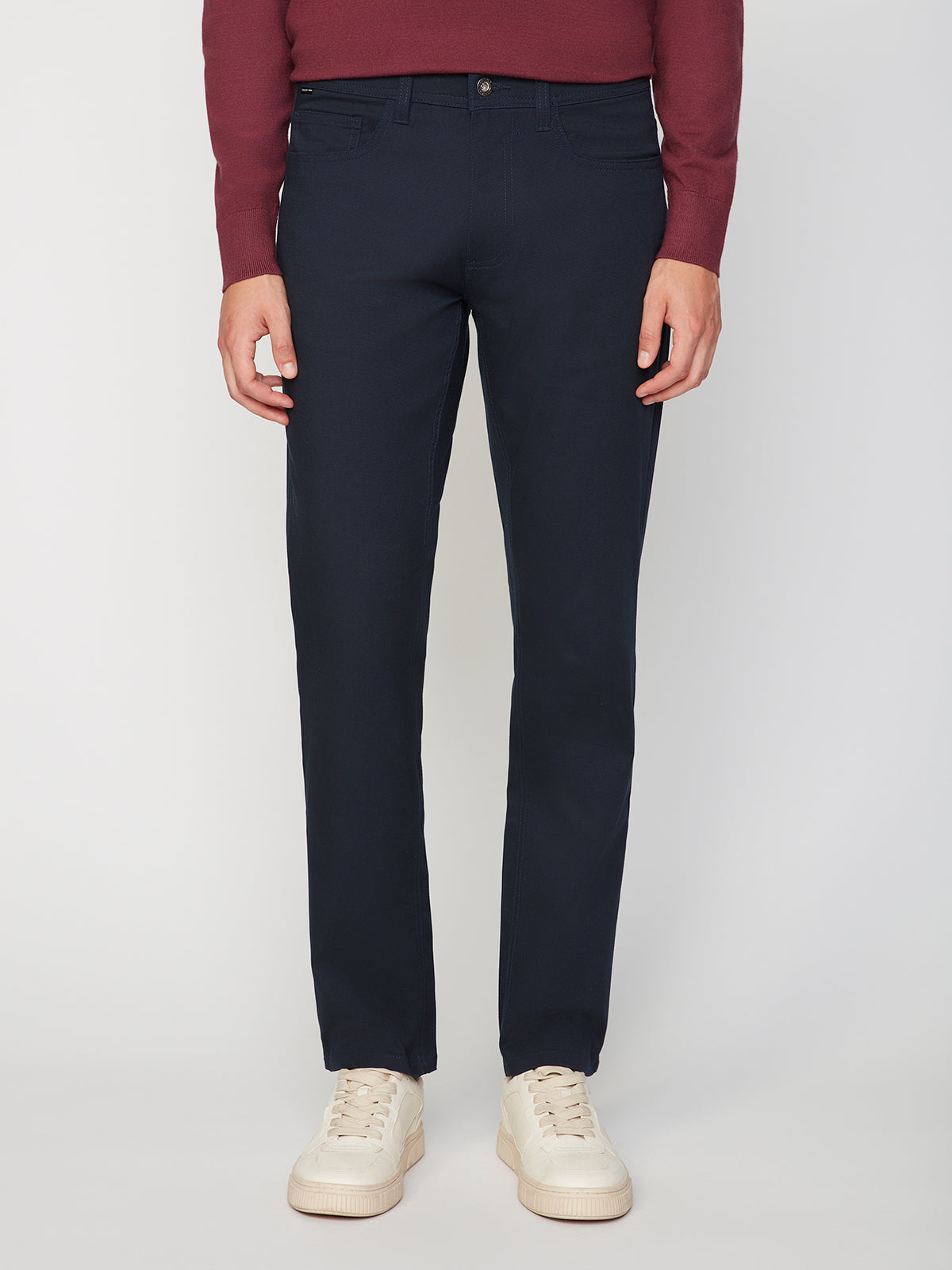 A person stands against a white background, showing only the lower torso and legs, wearing PROJEK RAW MENS CANVAS BUNGEE 5-POCKET PANT in dark navy, paired with a burgundy long-sleeve shirt and white sneakers.
