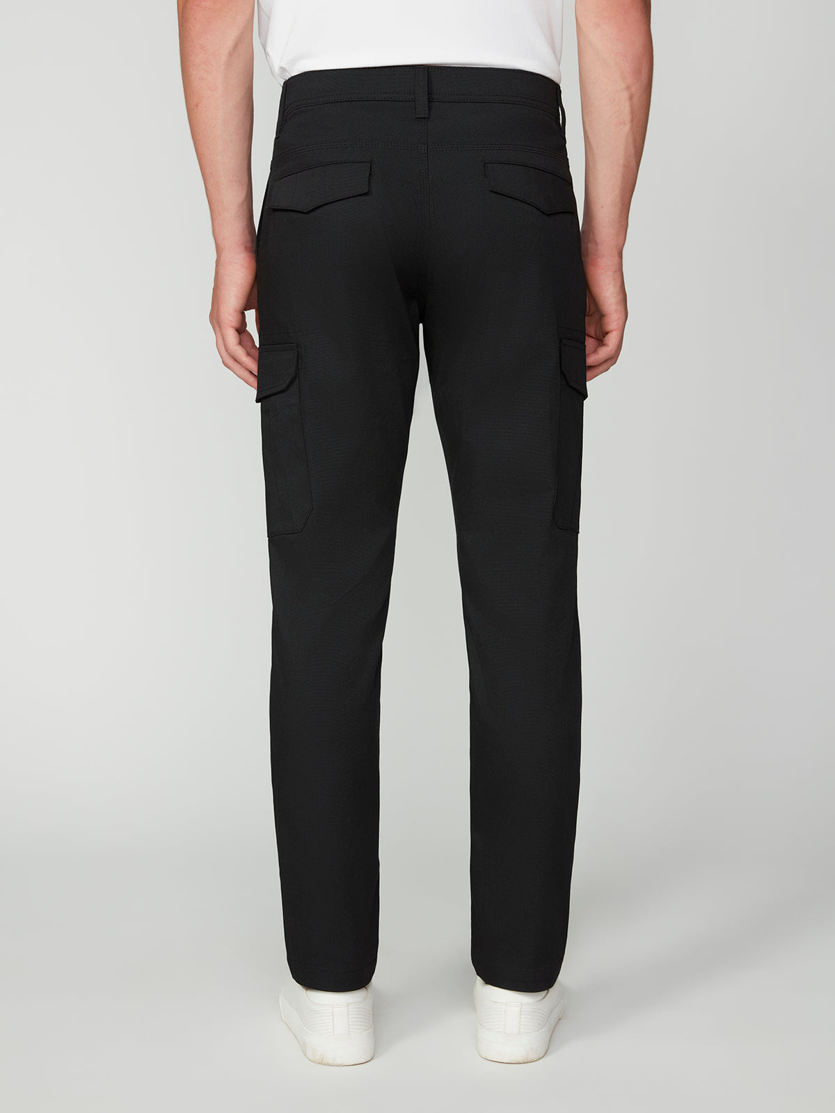 A person is shown from the back wearing PROJEK RAW MENS CANVAS BUNGEE RELAXED CARGO PANT in black with a bungee waistband and white sneakers, standing against a plain light background.