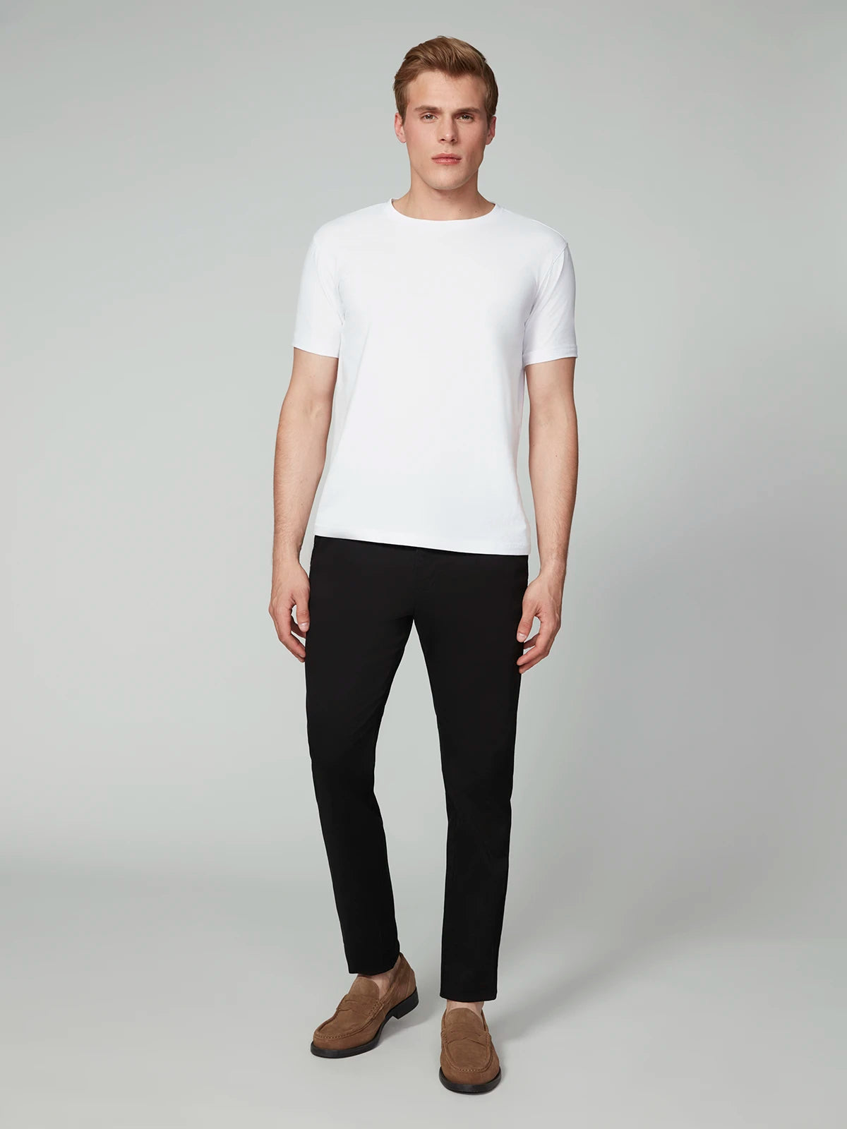 A man stands facing forward against a plain background, wearing a white short-sleeve t-shirt with PROJEK RAW MENS CHINO SIGNATURE WOVEN PANT and brown suede loafers.