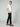 A man stands sideways with one hand in his pocket, wearing a white t-shirt, PROJEK RAW MENS CHINO SIGNATURE WOVEN PANT in a tailored fit, and brown loafers against a plain light background.