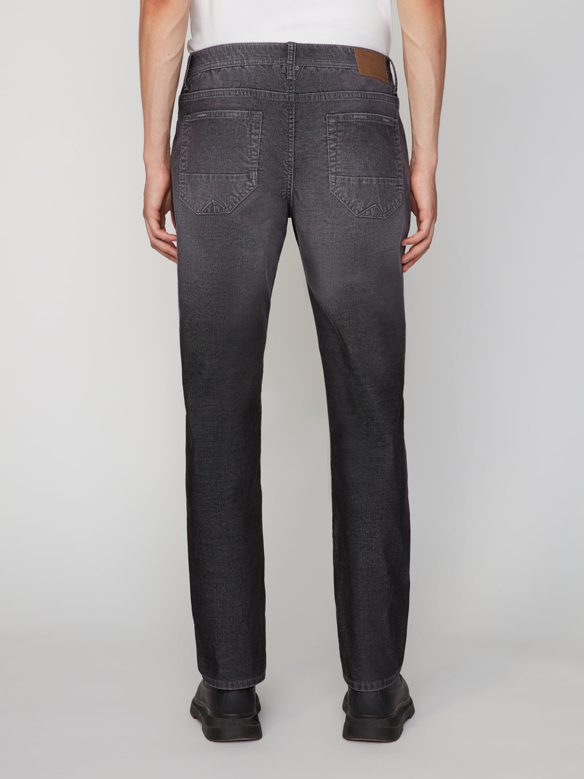 A person models the PROJEK RAW MENS BARU5-POCKET STRAIGHT FIT DENIM PANT with black shoes, shown from the back against a white background, displaying only the lower half of their body.