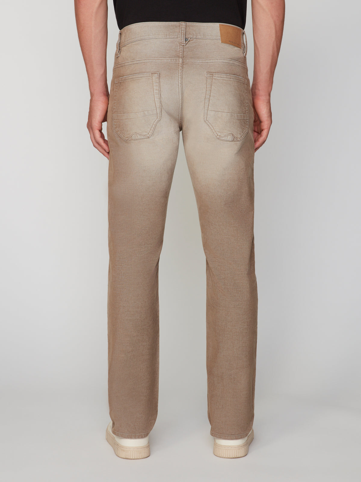 A person is shown from the back wearing PROJEK RAW MENS BARU5-POCKET STRAIGHT FIT DENIM PANT in light brown with a comfort waistband and white sneakers, standing against a plain light gray background.