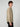 A young man with curly brown hair stands sideways facing left, wearing a PROJEK RAW MENS LONG SLEEVES CORDUROY SHIRT in light tan with chest pockets and black pants against a plain light gray background.