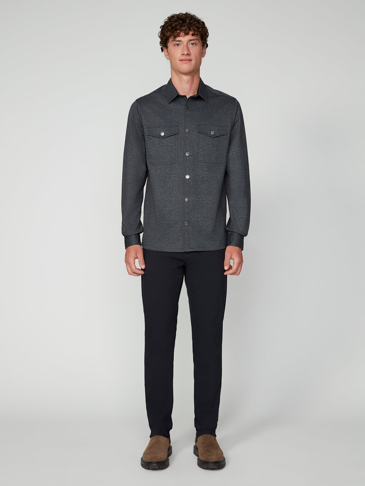 A young man faces forward wearing a PROJEK RAW MENS LONG SLEEVES KNIT SHIRT, black pants, and brown shoes against a plain light grey background.