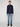 A person with short light brown hair stands facing forward, wearing a PROJEK RAW MENS LONG SLEEVES KNIT FLANNEL SHIRT, light blue jeans, and black shoes against a plain light background.