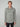 A man with short light brown hair models the PROJEK RAW MENS LONG SLEEVE SHERPA LINED OVERSHIRT, a light gray button-up shirt jacket with front pockets and black buttons, against a plain light gray background.