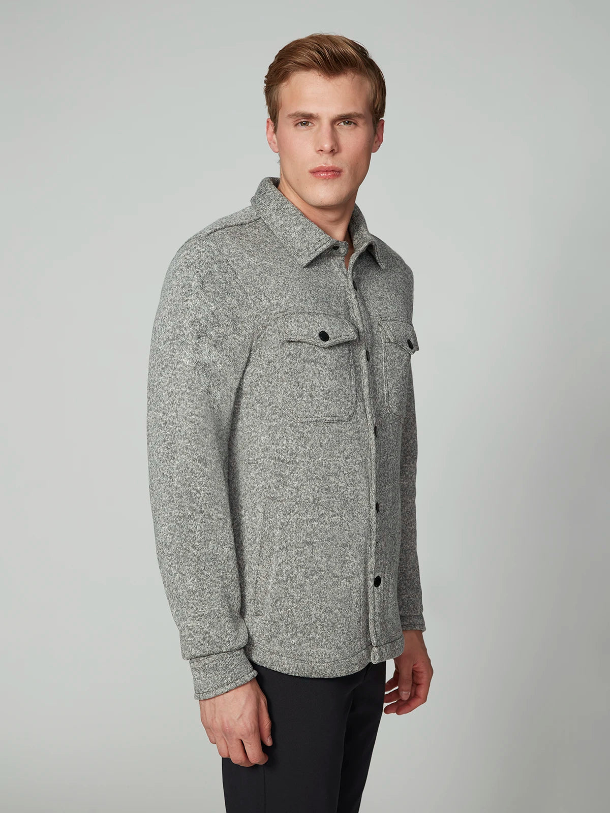 A man with short light brown hair models the PROJEK RAW MENS LONG SLEEVE SHERPA LINED OVERSHIRT—gray with chest pockets and black buttons—standing against a plain light gray background.