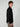 A young man with curly brown hair wears the PROJEK RAW MENS LONG SLEEVE FAUX SUEDE OVERSHIRT in black and taupe pants, posing sideways against a light gray background—the perfect lightweight layer for any outfit.
