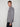 A person with short light brown hair wears the PROJEK RAW MEN’S STRETCH FAUX SUEDE OVERSHIRT in gray and dark pants, standing sideways and looking at the camera against a plain light background.