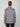 A person with short brown hair stands with their back to the camera, wearing the PROJEK RAW MEN’S STRETCH FAUX SUEDE OVERSHIRT in light gray and dark jeans against a plain light background.