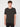 A young man with short curly brown hair wears the PROJEK RAW MENS SHORT SLEEVE CREW NECK T-SHIRT in black with black pants, standing facing forward against a white background.