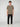 A young man with short curly hair stands facing forward in a simple gray setting, wearing a PROJEK RAW MENS SHORT SLEEVE CREW NECK T-SHIRT in olive green, black cargo pants, and white sneakers.
