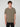 A young man with curly brown hair wears a PROJEK RAW MENS SHORT SLEEVE CREW NECK T-SHIRT in olive green and black pants, standing facing forward against a light gray background for a casual look.