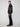 A person with short light brown hair stands sideways, wearing a black leather jacket, PROJEK RAW MENS STRETCH SLIM FIT JEAN, and black boots against a plain light gray background.