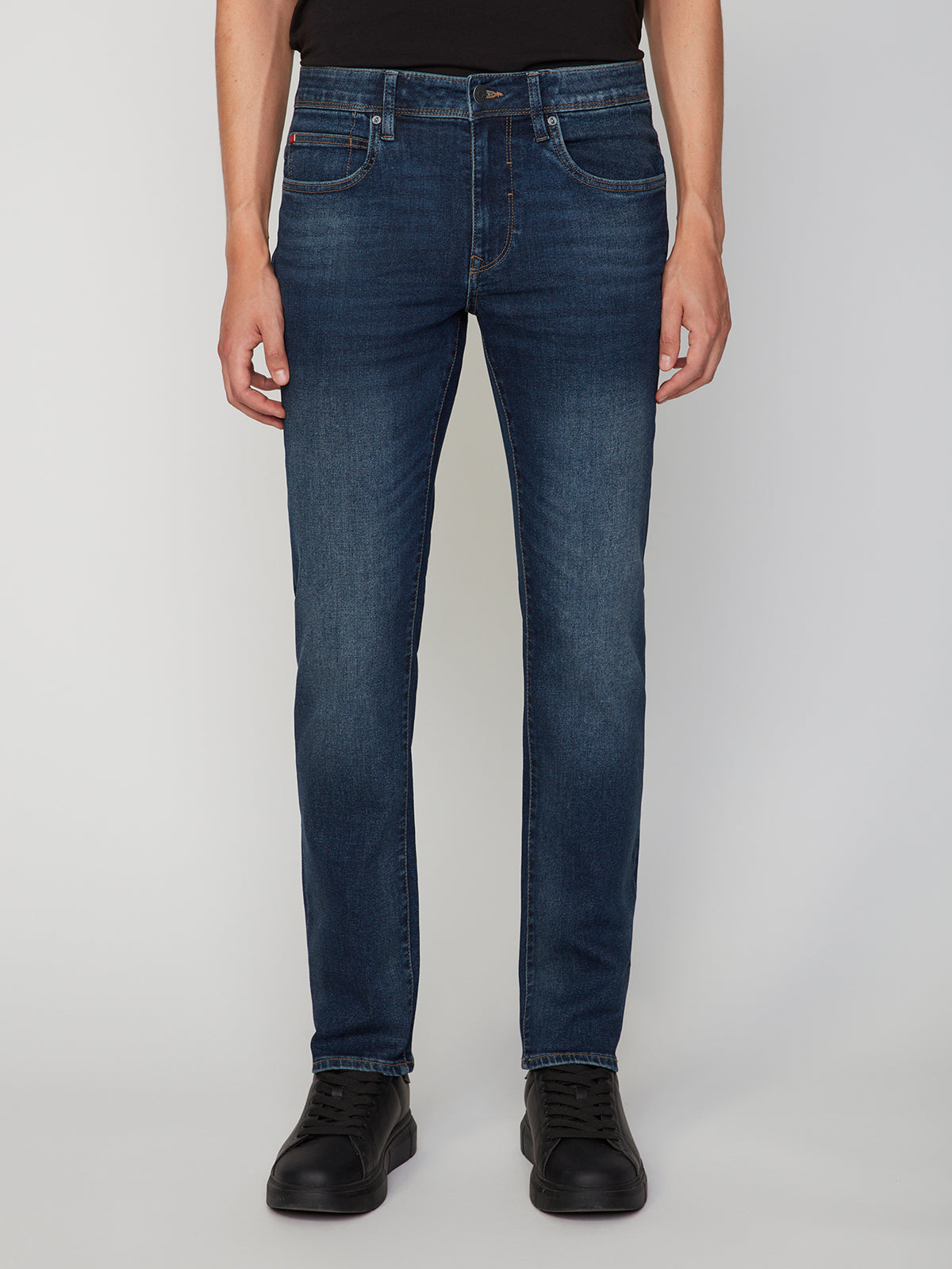 A man wearing PROJEK RAW MENS BARU STRAIGHT FIT JEAN in dark blue denim, a black shirt, and black shoes stands against a plain light gray background, visible from shoulders to feet.