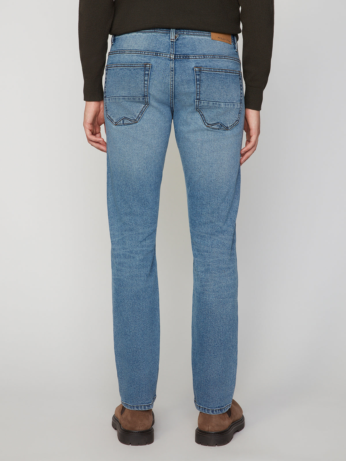 A person wearing PROJEK RAW MENS BARU STRAIGHT FIT STRETCH JEAN in light blue with brown shoes is shown from the back against a plain white background.