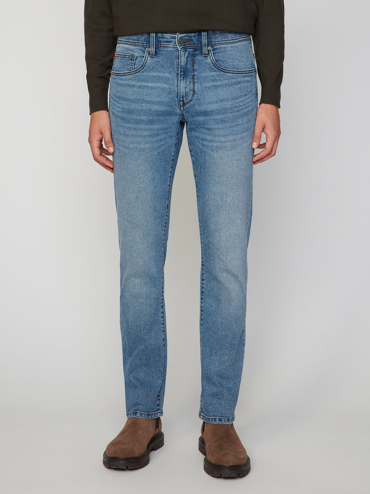 A person wears the PROJEK RAW MENS BARU STRAIGHT FIT STRETCH JEAN in light blue, styled with a dark sweater and brown boots. The lower half is shown against a white background, highlighting a classic Projek Raw look.