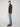 A man stands in profile against a plain light background, wearing a dark zip-up sweater, PROJEK RAW MENS BARU STRAIGHT FIT STRETCH JEAN, and brown boots.