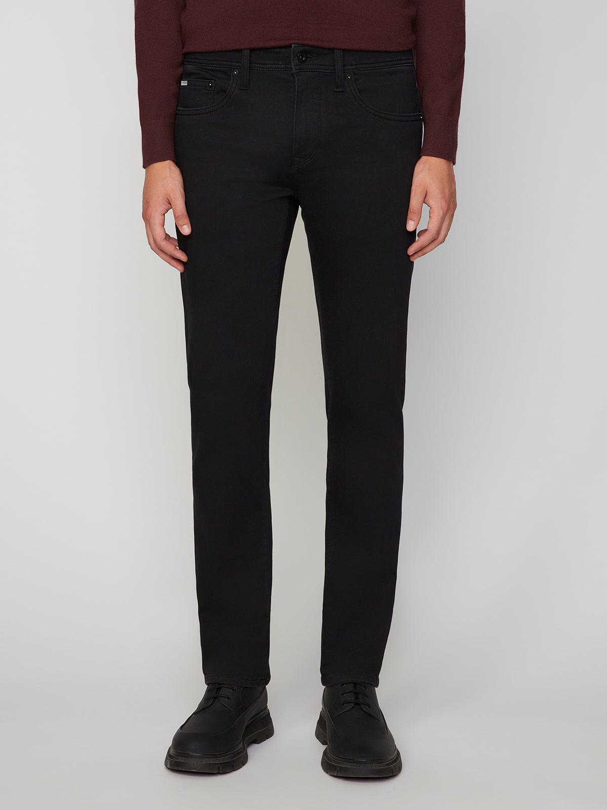A person is wearing PROJEK RAW MENS BARU STRAIGHT FIT COLORED DENIM JEAN, paired with a burgundy long-sleeve top and black dress shoes, standing against a plain light background. Only the lower torso and legs are shown.