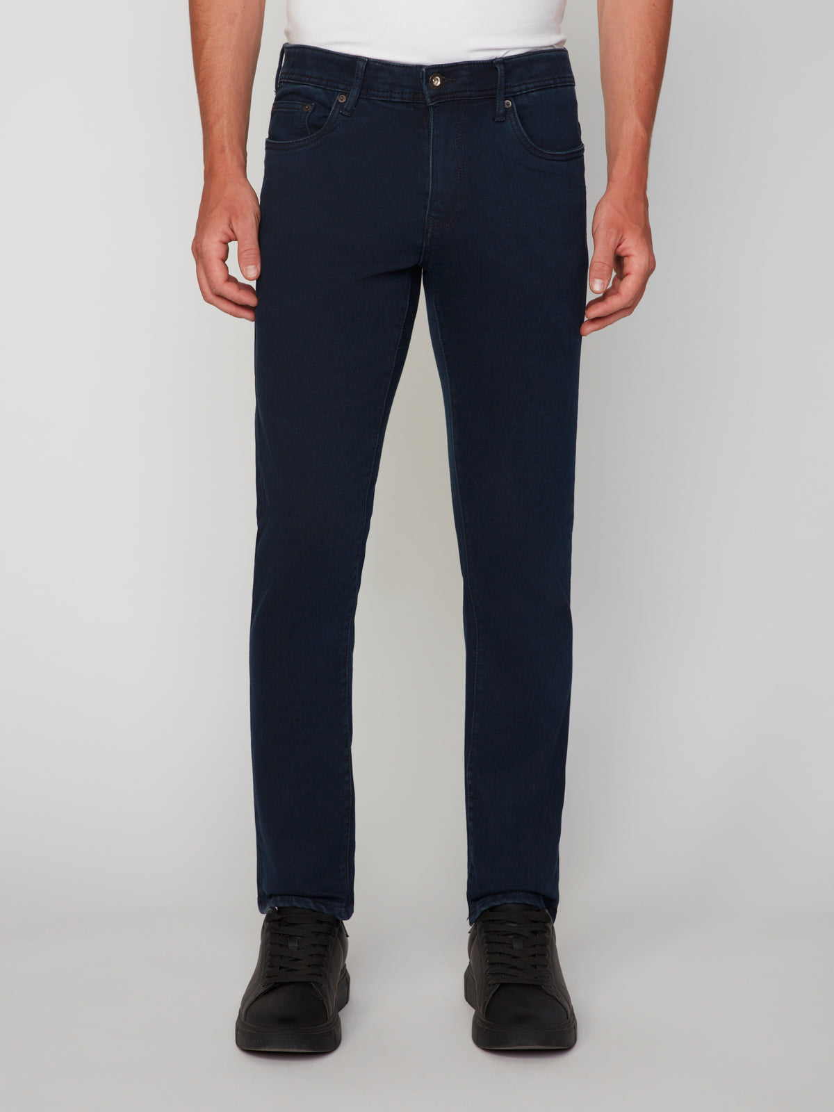 A person wears PROJEK RAWs MENS BARU STRAIGHT FIT COLORED DENIM JEAN, a tucked-in white shirt, and black sneakers, standing against a plain light gray background. The image focuses on the lower body from waist to shoes.