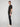 A person with short hair stands in profile against a plain background, wearing a black t-shirt, white sneakers, and PROJEK RAW MEN’S STRETCH SLUB DENIM BARU STRAIGHT FIT PANT.
