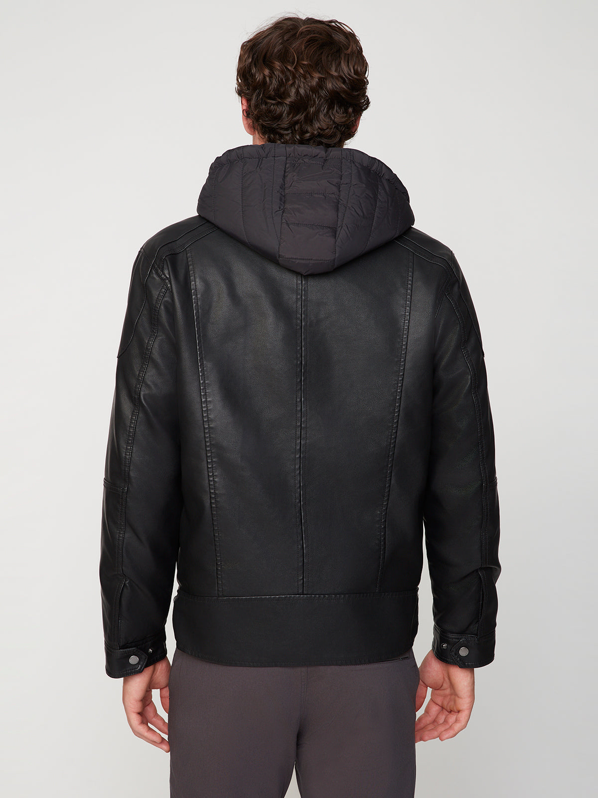 A man is seen from behind wearing the PROJEK RAW MENS MOTO JACKET WITH REMOVABLE HOODED DICKIE and dark pants, standing against a plain light background.