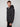 A man with short light brown hair wears the PROJEK RAW MENS HOODED FAUX FUR LINED PUFFER JACKET and black pants, standing slightly turned to the side against a plain light gray background.