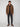 A person stands against a plain background wearing the PROJEK RAW MENS HOODED FAUX FUR LINED PUFFER JACKET for warmth, paired with a black shirt, dark pants, and brown suede boots. The jacket is zipped and hooded; they face forward with a neutral expression.