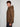 A young man with curly hair stands sideways, showcasing the cold-weather comfort of the PROJEK RAW MENS HOODED FAUX FUR LINED PUFFER JACKET with horizontal quilting and black pants, against a plain light background.