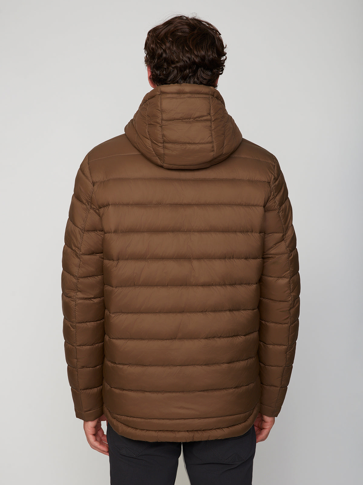 A person with short brown hair is seen from the back, wearing the PROJEK RAW MENS HOODED FAUX FUR LINED PUFFER JACKET and dark pants, standing against a plain light gray background.