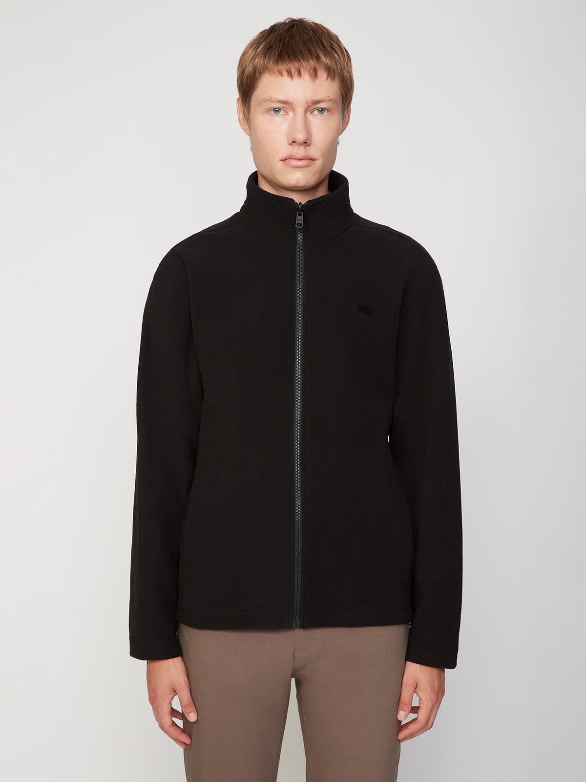 A person with short light brown hair models the PROJEK RAW MENS 3 IN 1 WATERPROOF JACKET in black and brown pants, standing against a plain light background, facing the camera with a neutral expression.
