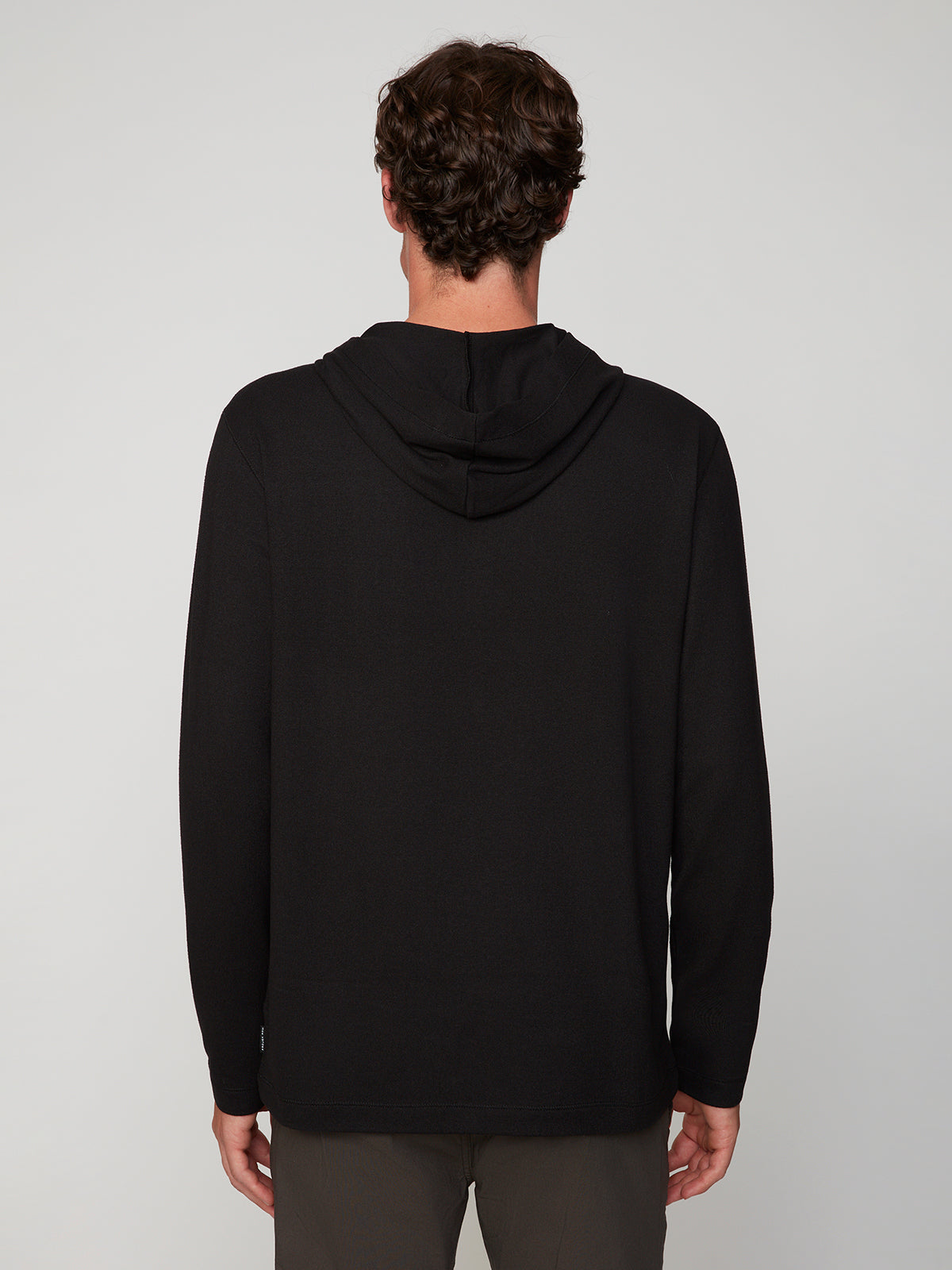 A person with short, curly brown hair is seen from the back wearing a PROJEK RAW MENS HOODED LONG SLEEVE KNIT and dark pants, styled against a plain light gray background.
