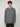 A young man with curly brown hair stands against a plain light gray background, wearing the PROJEK RAW MENS HOODED LONG SLEEVE KNIT. He has a neutral expression and relaxed posture, exuding casual comfort.