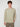 A young man with curly brown hair wears a PROJEK RAW MENS LONG SLEEVE CREW NECK KNIT in light beige and brown pants, standing against a plain light background, facing forward with one hand in his pocket.