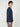 A young man with curly brown hair wears a PROJEK RAW MENS LONG SLEEVE CREW NECK shirt in navy blue and brown pants, standing in profile against a plain white background.