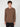 A young man with curly brown hair wears a PROJEK RAW MENS LONG SLEEVE CREW NECK in plain brown, classic fit with a chest pocket and black pants, standing against a light background, facing forward with a neutral expression.