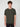 A young man with curly brown hair faces forward against a plain background, wearing a PROJEK RAW MENS SHORT SLEEVE CREW NECK GRID JERSEY OVERSIZE TSHIRT in textured dark green and black pants for a relaxed, casual style.