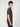 A young man with curly brown hair stands sideways, wearing a PROJEK RAW MENS SHORT SLEEVE CREW NECK GRID JERSEY OVERSIZE TSHIRT and black pants, displaying a relaxed, casual look against a plain light background.