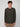 A young man with short curly hair wears a classic fit PROJEK RAW MENS LONG SLEEVE HENLEY GRID JERSEY in dark green and tan pants, standing against a plain light gray background and facing the camera neutrally.